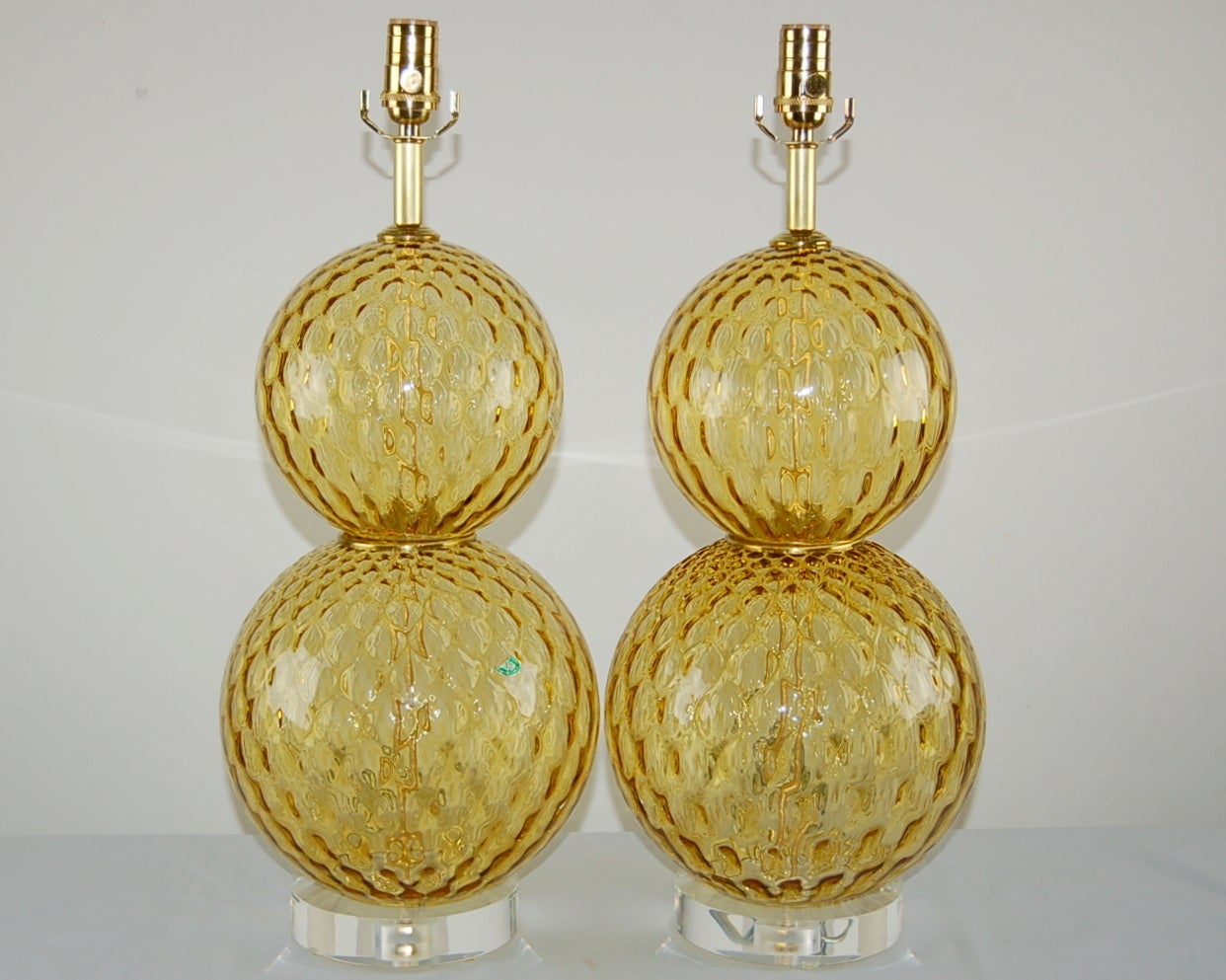 Stacked ball lamps of HARVEST GOLD, with brass wafers at the waist. Great texture to the glass provide a magical look, courtesy of the netted optics. 

The lamps measure 23 inches from tabletop to socket top. As shown, the top of shade is 28