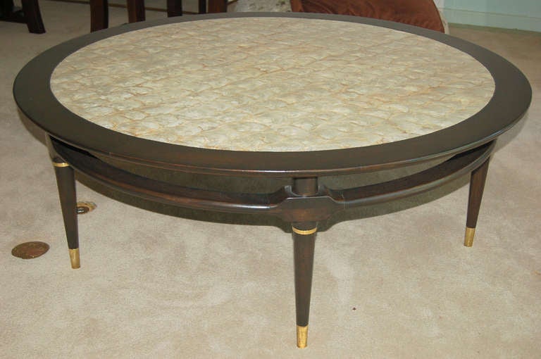 Stunning capiz shell-topped coffee table of chocolate brown from 1964 in perfect condition! Collar ring ornamentation and sabots of solid brass. Attributed to Monteverdi-Young. 

The table stands 18.5 inches high. It is 52 inches in diameter and