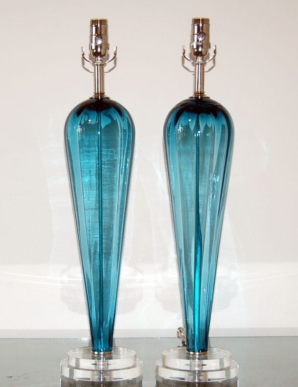 These inverted teardrop lamps feature a broad shouldered silhouette in eye catching Teal Blue.  The glass has subtle facets, as can be seen in the lead photo.

We have paired these with nickel hardware and mounted them on two tiered bases.  The