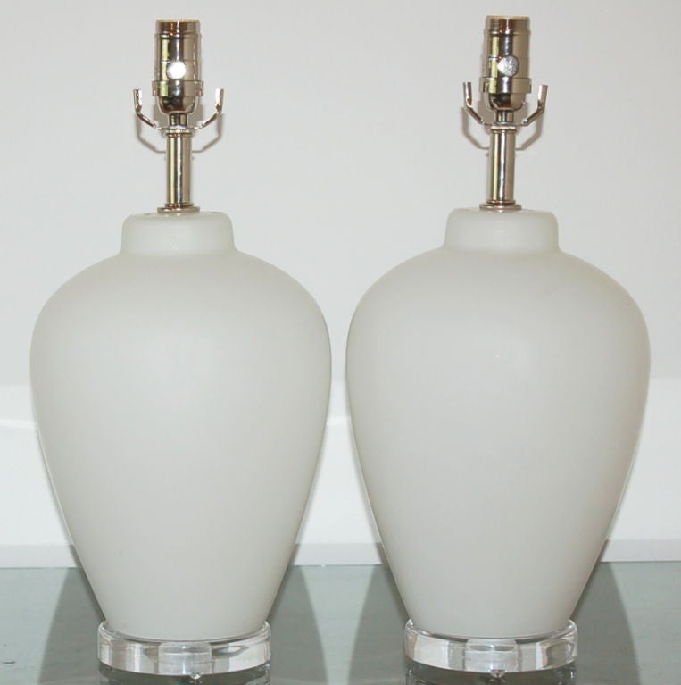 Perfectly proportioned for bedside or vanity, these white vintage Murano lamps are opaque with a satin acidato finish.  Lucite wafer base and nickel plated hardware give them a simple, elegant look.

The lamps measure 18.5 inches from tabletop to