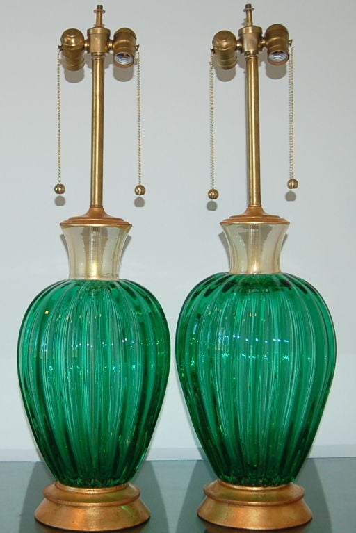 Matched pair of vintage EMERALD GREEN Murano glass lamps with 24-karat gold collars mounted on gold-leafed wood bases. These are signature Archimede Seguso lamps as perfect as they were fifty years ago!

The lamps are 30 inches from tabletop to