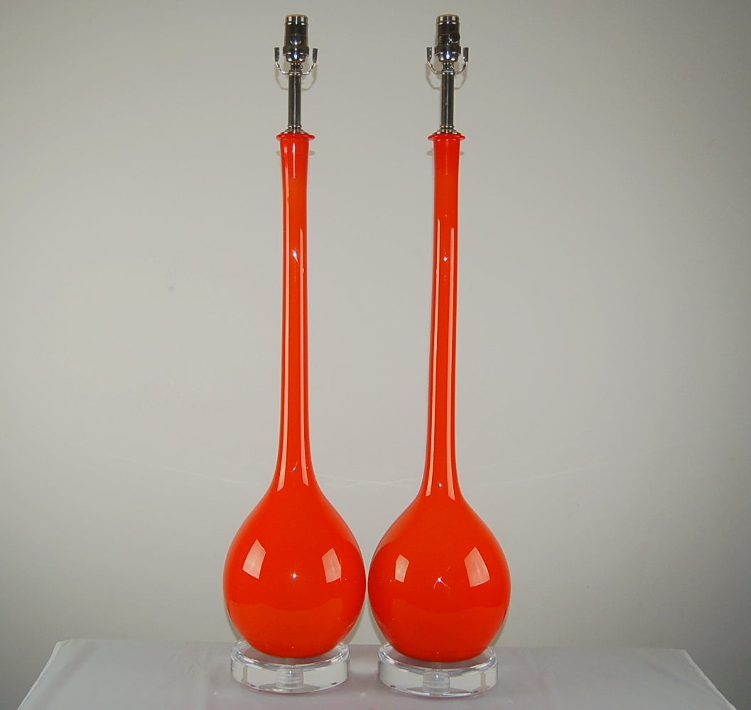 Long necked shape by Archimede Seguso, imported in the 1960s. A layer of whited cased glass is surrounded by a thick layer of VERMILLION glass, with Lucite base and nickel hardware.

They are 38 inches to the socket top; the glass alone is over 32