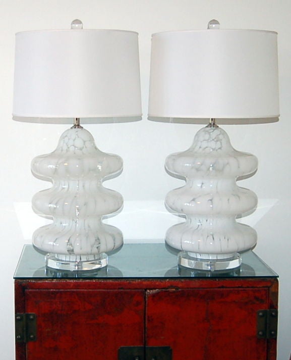 Very stylish Murano lamps from the late 1960s in a rarely seen three-tiered style. We've plated these on Lucite chunks, giving the lamps a cantilevered look.

The lamps measure 22 inches to the socket top. As shown, the top of shade is 28 inches