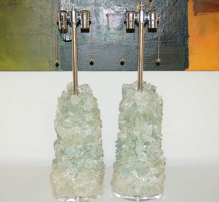 Newly built pair of sculpted recycled glass cluster lamps in CLEAR ICE, designed by Swank Lighting. Clear rock stacked on Lucite, with nickel plated hardware. 

The lamps are 27 inches tall from tabletop to socket top. As shown, the top of shade