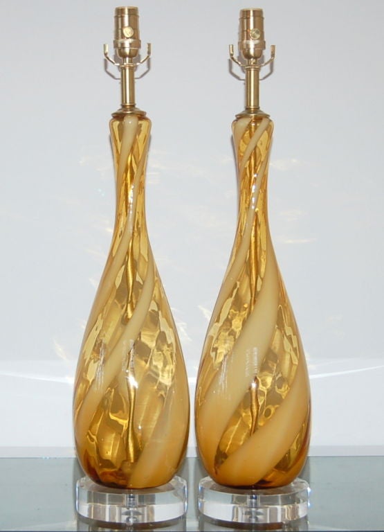 A whimsical pair of Italian lamps in BUTTERSCOTCH with a swirling ribbon of white. We show this pair on single lucite discs with solid brass hardware. 

The lamps measure 27 inches from tabletop to socket top. As shown, the top of shade is 33