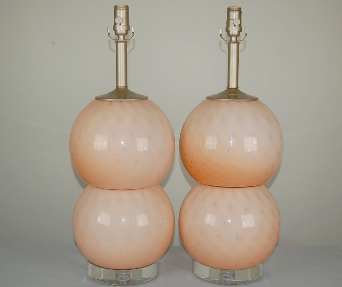 Vintage matched pair of Stacked Murano ball table lamps of PALE PINK, chocked full of large controlled bubbles. They are nipped at the waist by platinum colored rings. 

The lamps measure 23 inches from tabletop to socket top. As shown, the top of