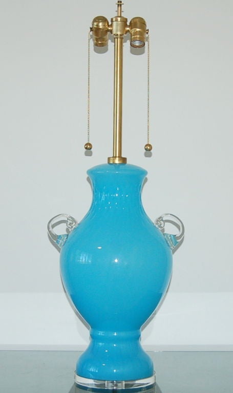 Wonderful urn shaped lamp of vintage Murano glass, circa 1950s. The color is a very intense sky blue with handles made of applied clear glass. We use satin brushed brass hardware including twin earring pulls.

We show this mounted on a simple