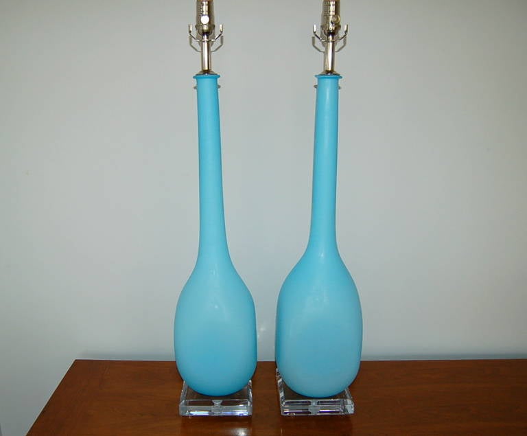 These long necked lamps are unique, as the glass is squared off at the base. A layer of whited cased glass is surrounded by a thick layer of SKY BLUE glass with a matte finish.

They stand 33 inches to the top of the socket. As shown, the top of