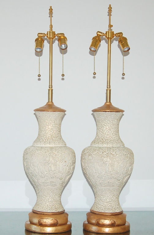 A very stylish pair of carved plaster lamps with an Asian bent.  Simple hourglass shape in BONE with gold leafed, James Mont styled base.

The lamps are 33 inches tall to the socket top.  As shown, the top of shade is 39 inches high.  Lampshades