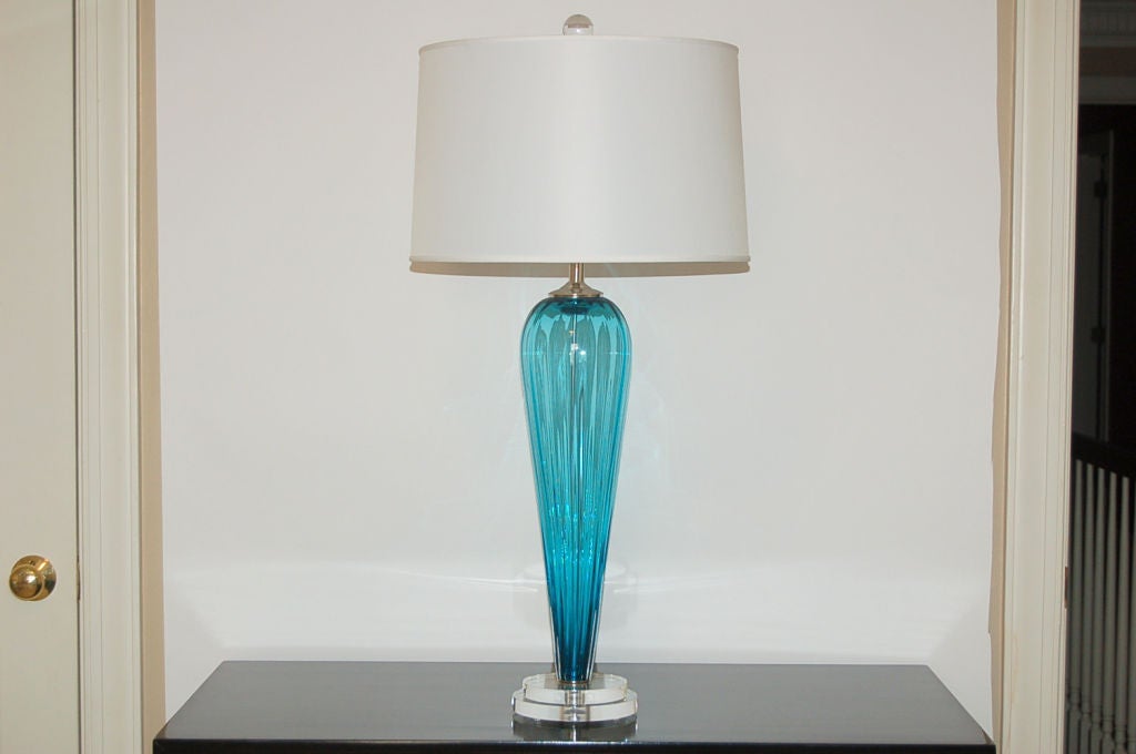 Exclusively blown for Swank Lighting by California artist Joe Cariati, these teal blue lamps are signed by the artist. Vertical ribs add visual texture to the teardrops. 

They measure 24 inches from tabletop to socket top. As shown, the top of