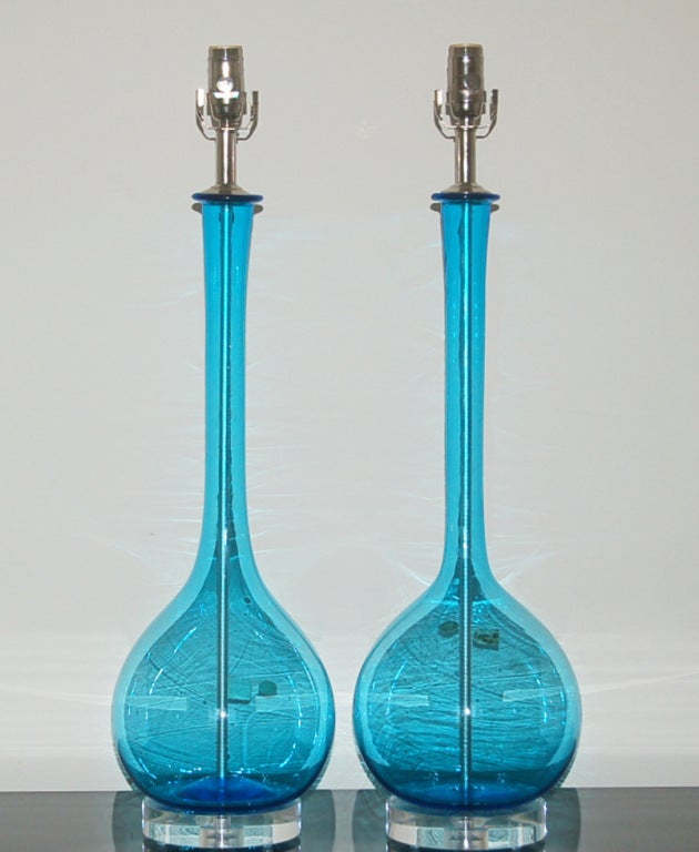 Sleek pair of vintage Murano lamps with long, slender necks by Archimede Seguso in SEE THROUGH SEA BLUE.   Such a luscious color and quite rare for us - two pair and we're out.  Shown with nickel plated hardware, mounted simply on Lucite.

The