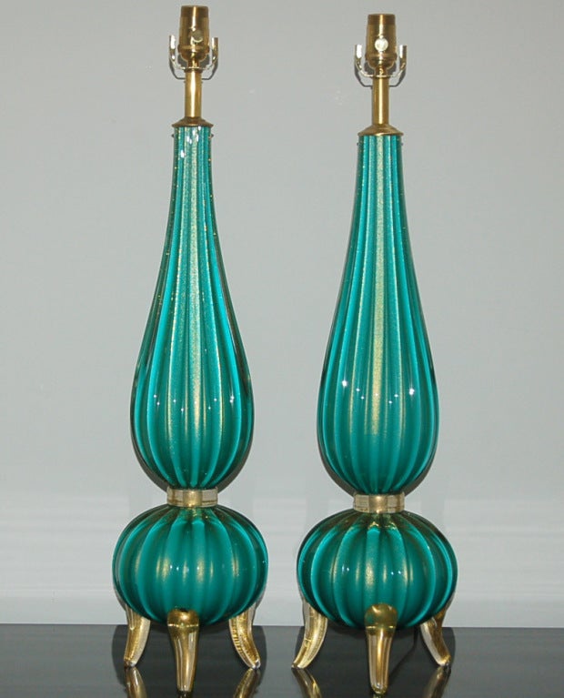 An elegant interpretation of the classic 1940's Barovier & Toso three-footed lamps. The glass is a bold DEEP AQUA, filled with GOLD dust. 

The lamps stand 31 inches to the socket tops. As shown, the top of shade is 37 inches high. Lampshades are