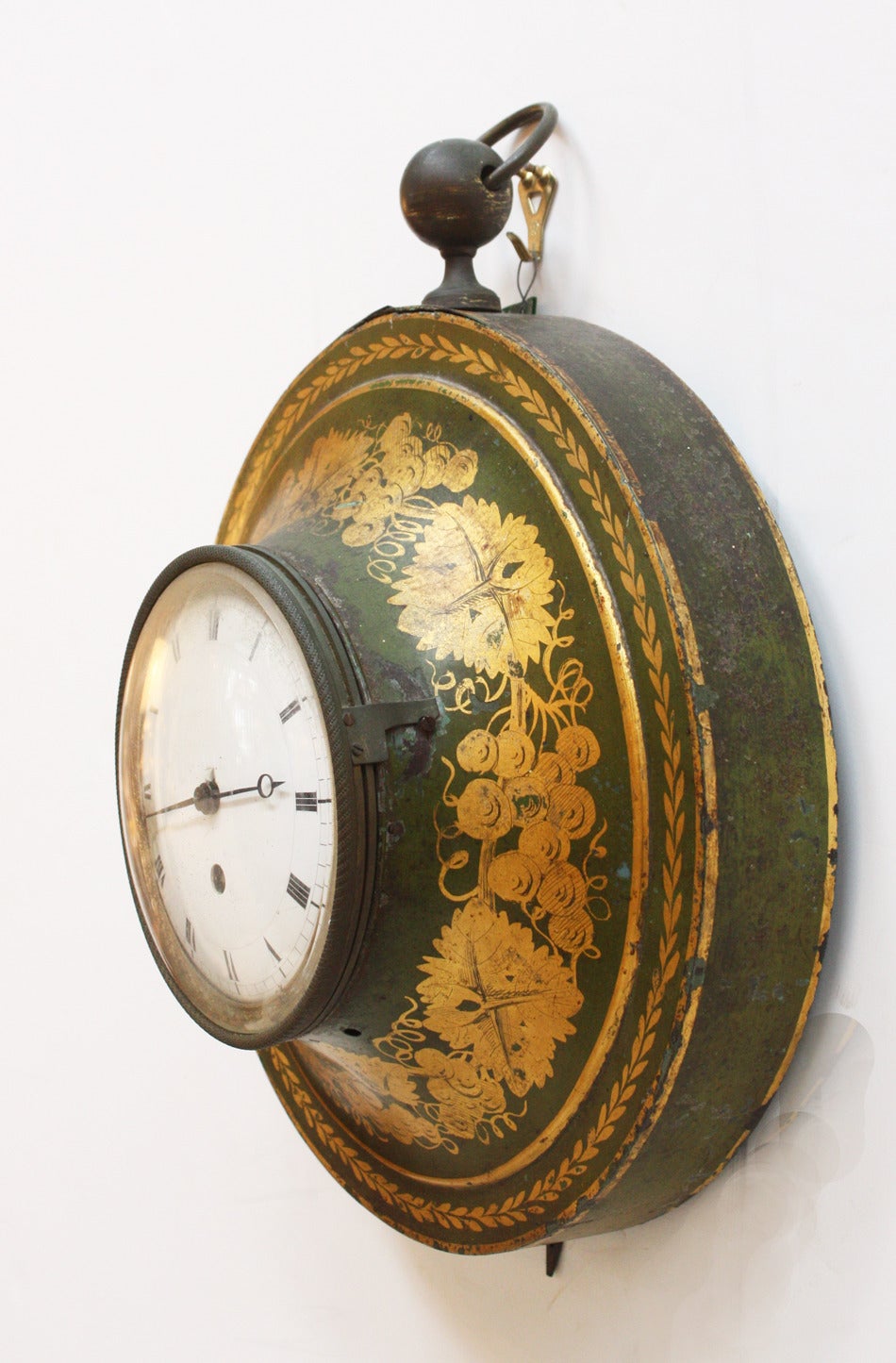 A round hanging tole clock, gold on black with green background.  England.  Late 19th Century.