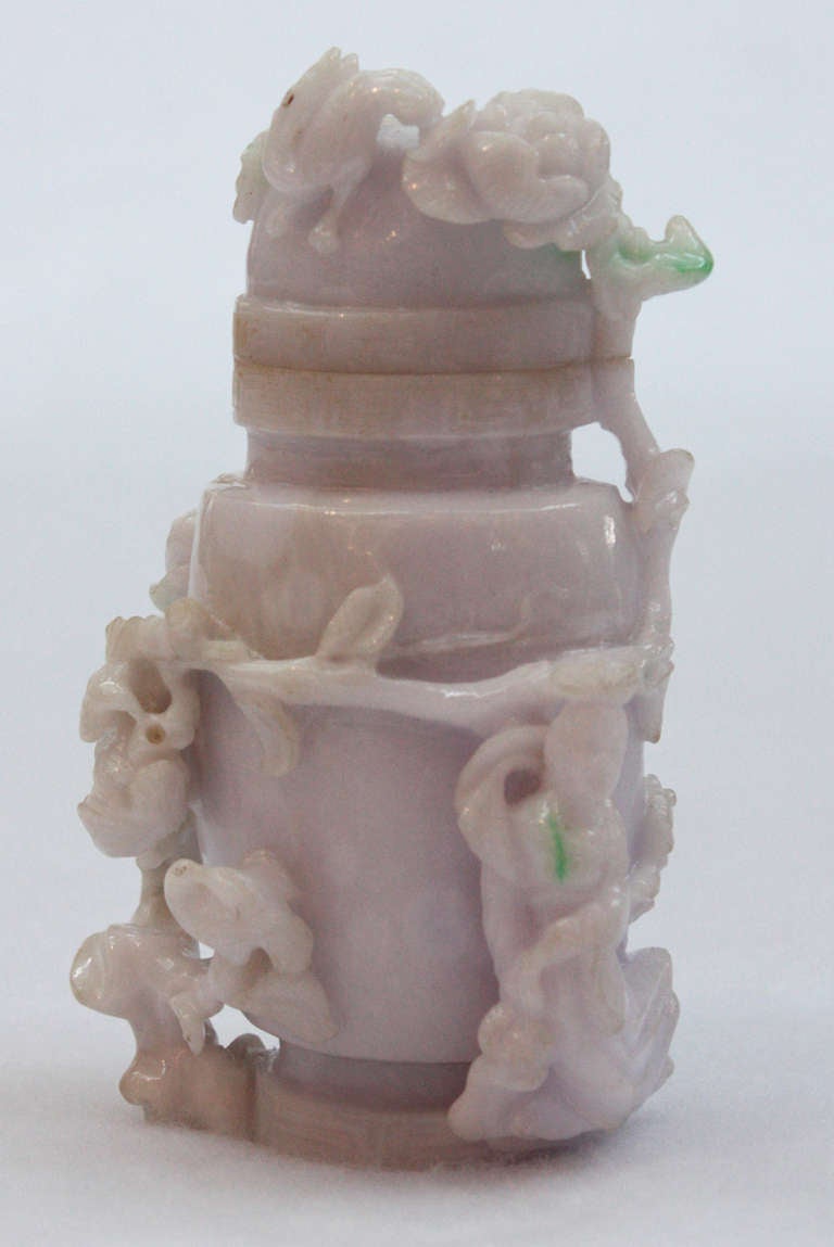 A Chines vase and cover, lavender jade with apple green inclusions. Flattened oval form with body and finial carved with flowering branches, woman and bird in high relief. Greek key design around top and bottom.