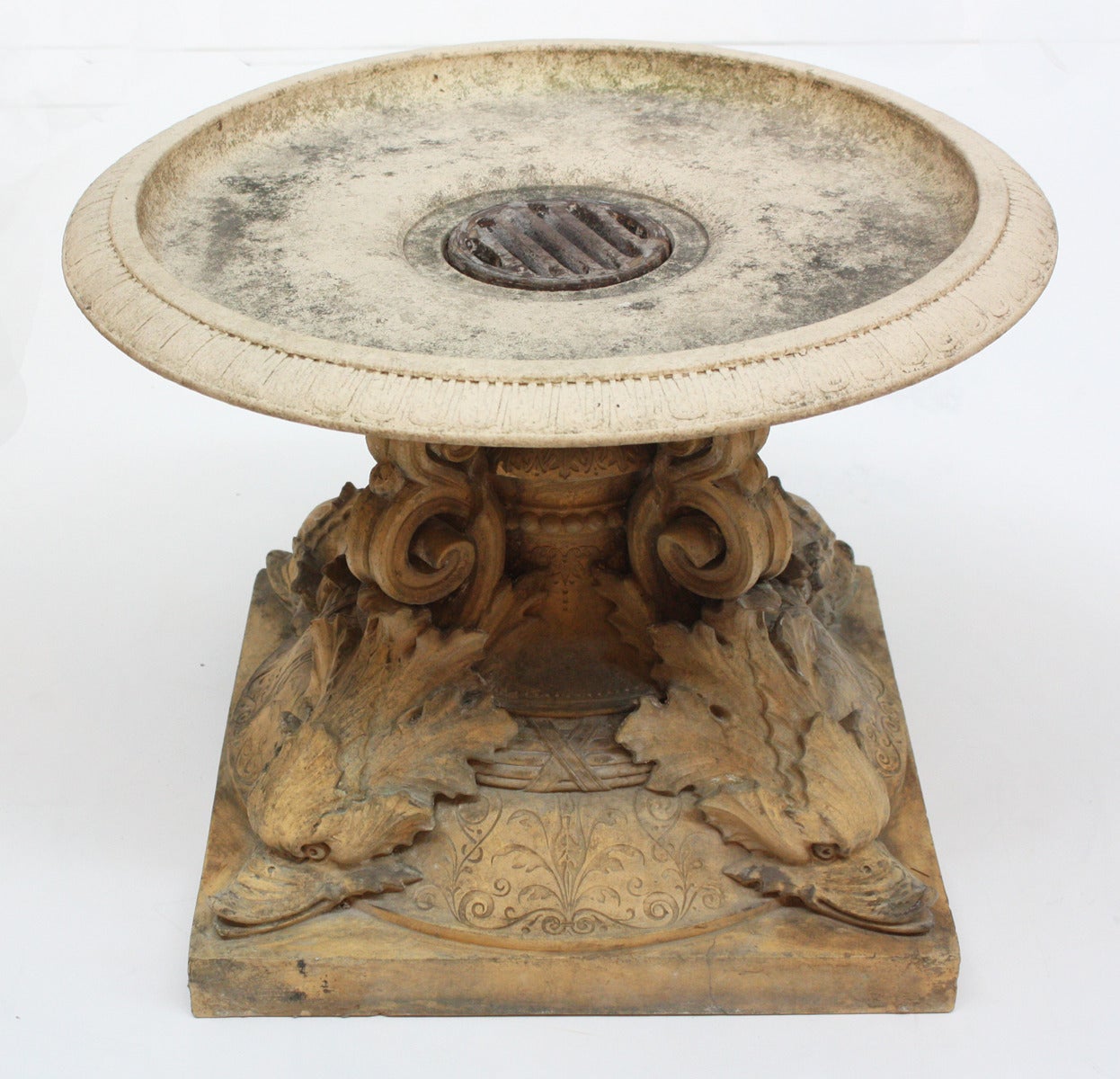 An ornate terra cotta fountain base with decorative upended dolphins supporting the top disc, England, late 19th century.