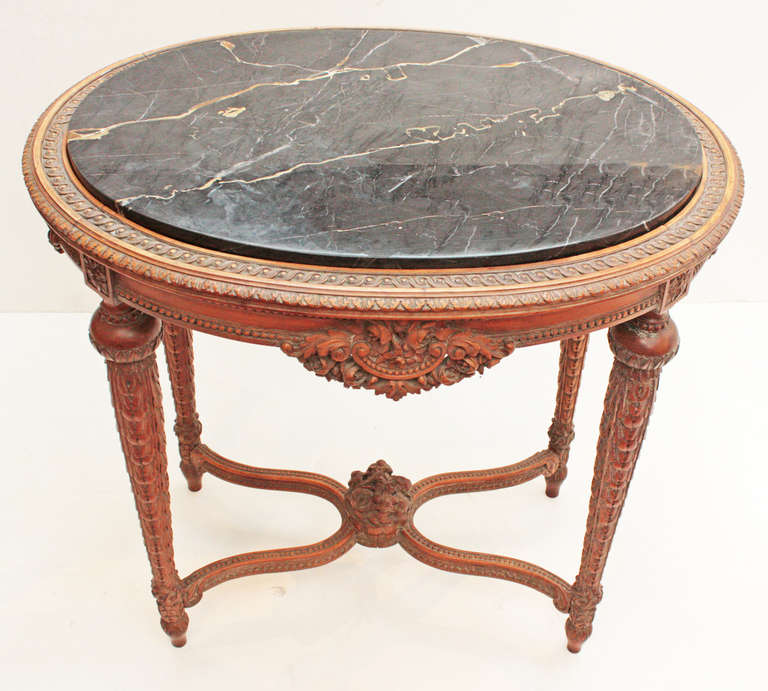 an oval Art Deco era occasional table in the Louis XVI manner, fruitwood with heavily carved legs and apron, double 