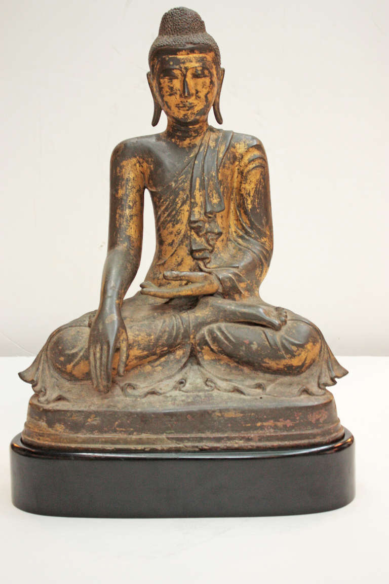 a large seated Buddha, bronze with worn gilt surface, on wooden stand