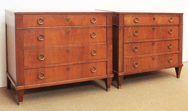 a circa 1960 pair of Neoclassical style walnut chests of drawers, circular pulls and shield form escutcheons by Baker Furniture