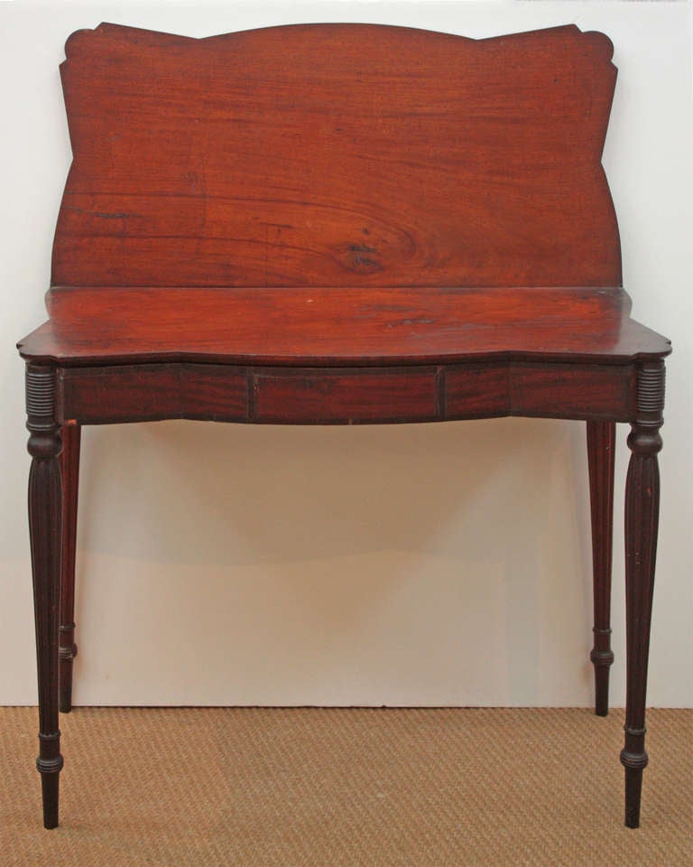 an American Sheraton mahogany card table with shaped bookmatched  lift top, reeded legs, from Massachusetts,  possibly by Seymour