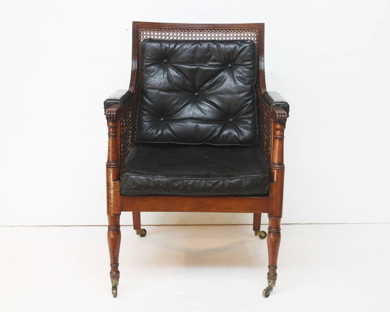 Period Regency library chair with caned back, sides and seat, turned front legs, castors, with leather cushions