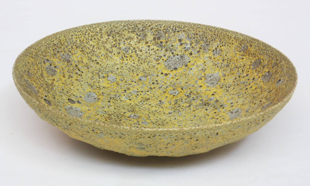A small shallow ceramic bowl with yellow lava glaze. Signed