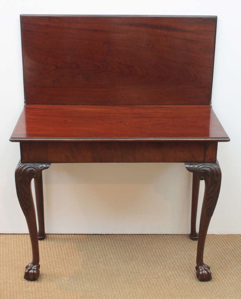 late 18th century flip top table of mahogany, scroll carved legs with acanthus leaf motif terminate in ball and claw feet on the front legs, the rear set 