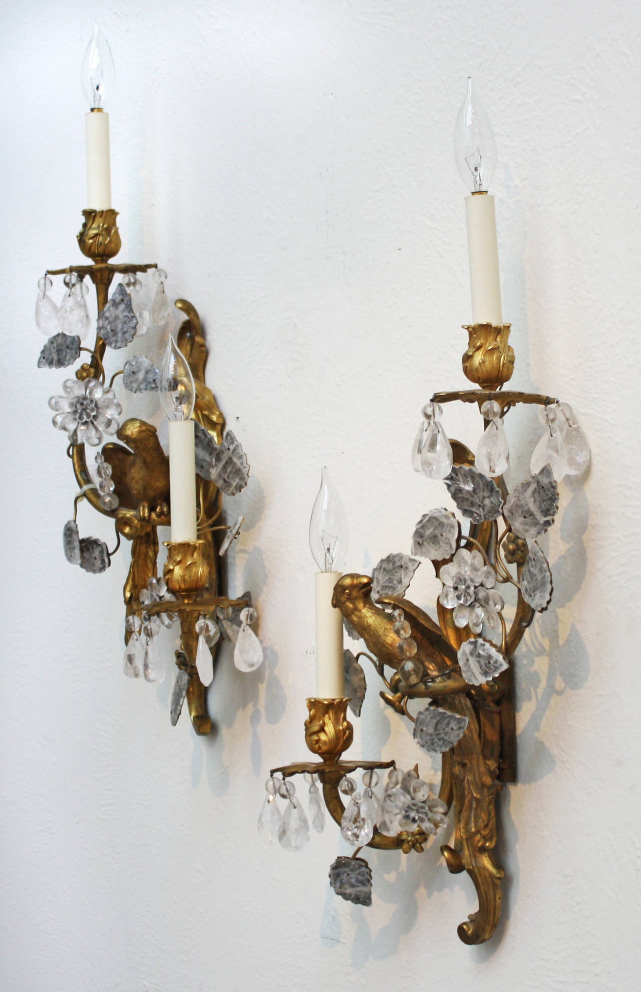A pair of superb Maison Bagues gilt bronze and rock crystal two light sconces decorated with parrots and flowers .