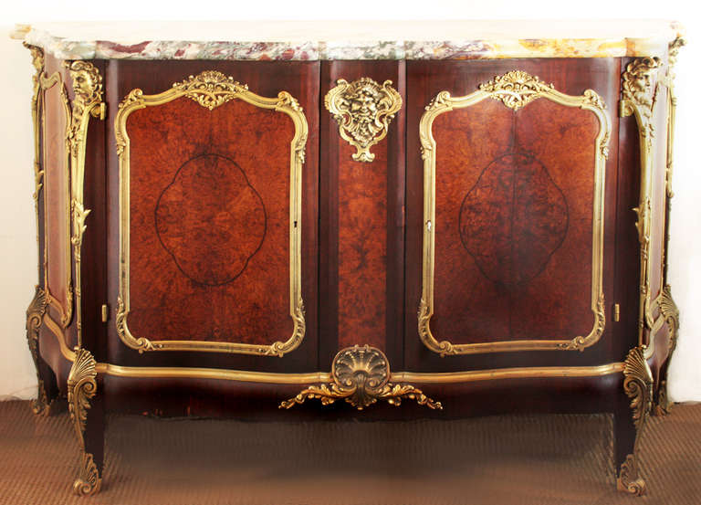 An ornate ormolu two door French mounted credenza with a single shelf, mahogany with serpentine burl walnut doors and side panels, topped with shaped breccia de vendome marble top (repaired)