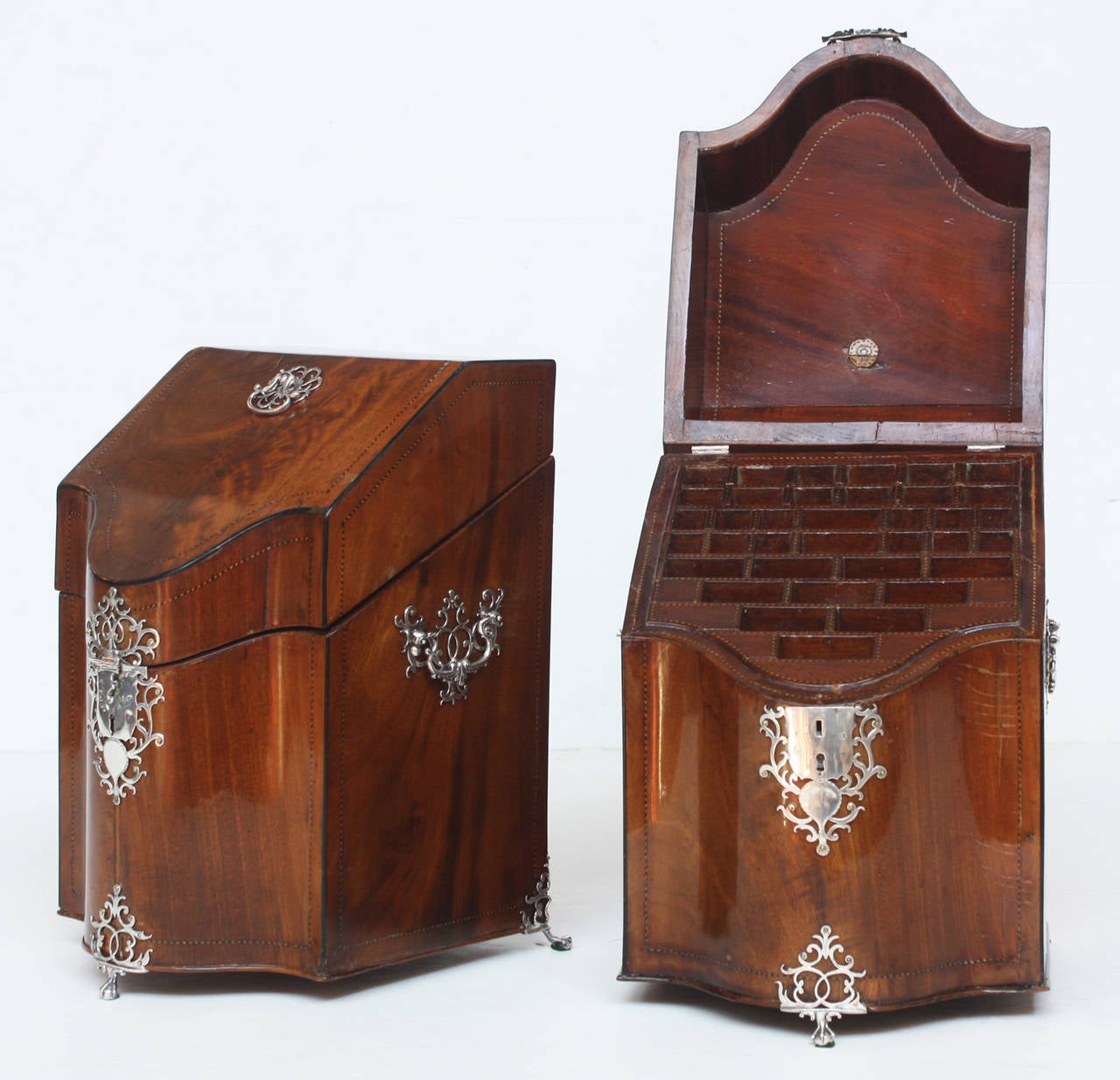 A pair of George III bookmatched mahogany and silver-mounted knife boxes. Both with serpentine front, sloping cover, on three silver claw-and-ball feet with pierced foliage above, and with similar silver lock plate. Each box has drop-ring handles