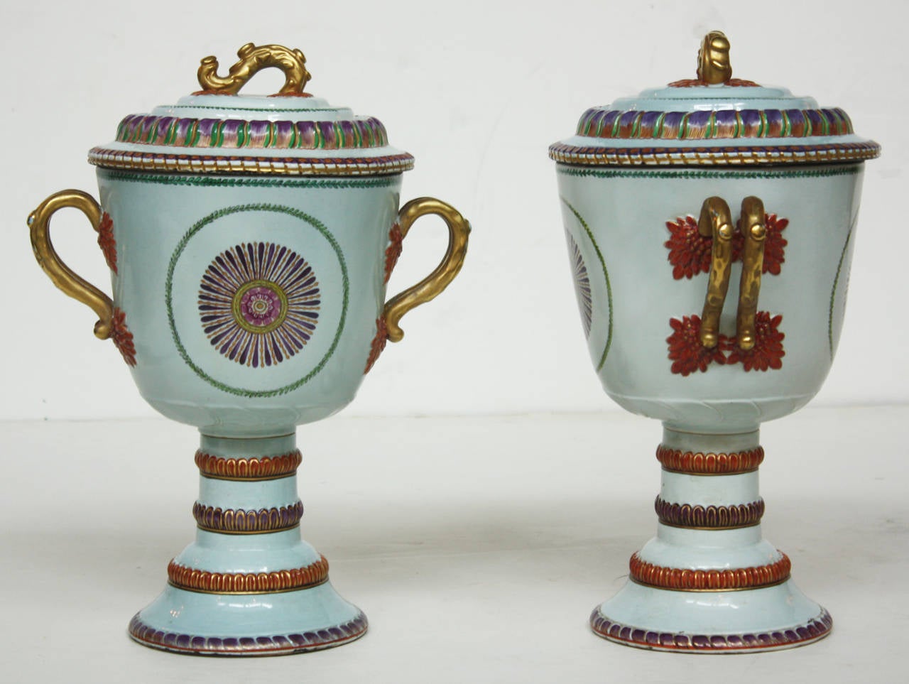 A pair of Chinese export porcelain jars with lids, urn-form, white with orange, purple and green design with gilt handles, diameter of base is 6