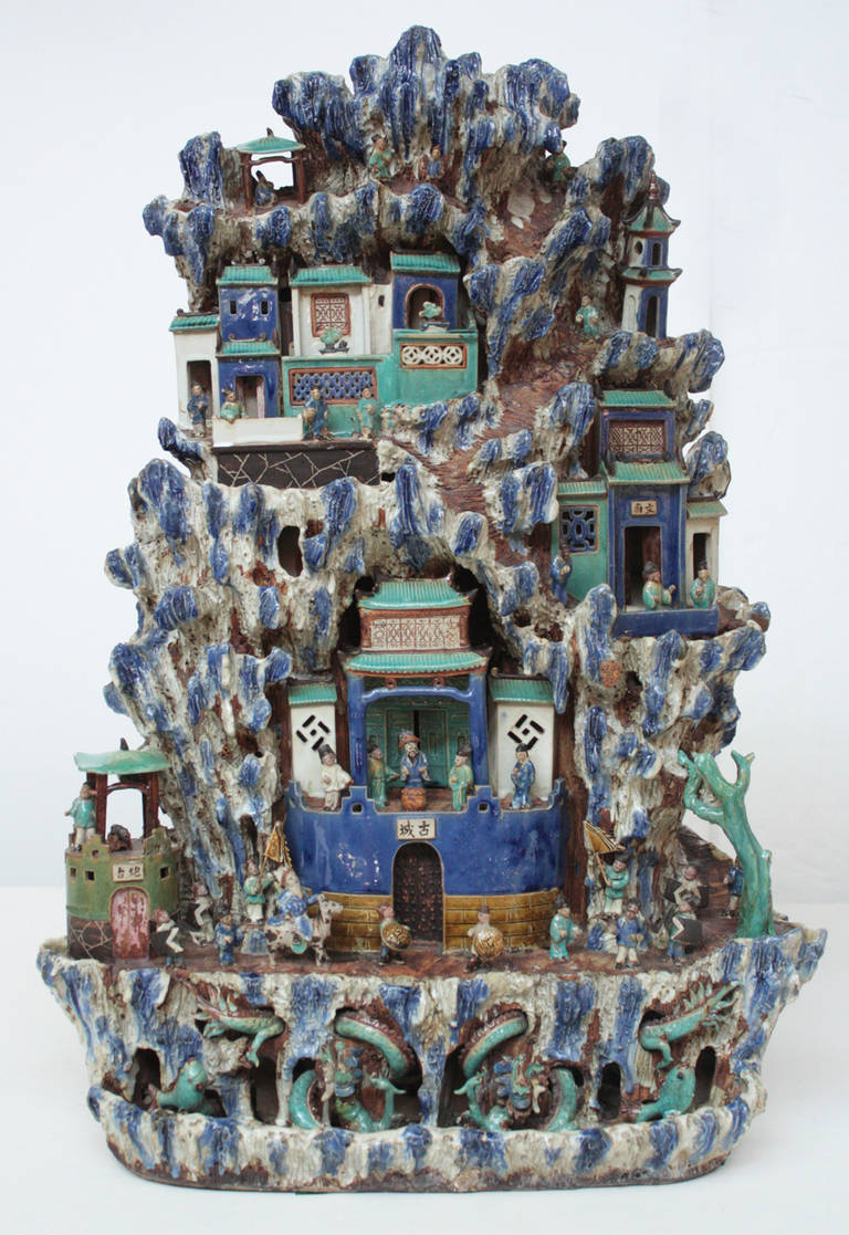 A large Chinese pottery fountain with stepped layers of trees, houses, people, dragons etc. Glazed in blues, greens and white predominantly.