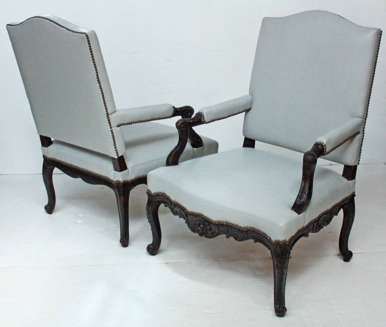 A large pair of early 18th century Regence open armchairs with new leather upholstery.