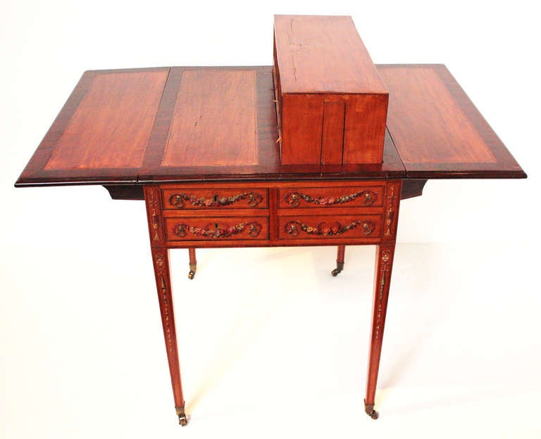 a beautiful Harlequin Pembroke of satinwood and mahogany, two long drawers with two faux drawers all with painted floral swags, an ingeniously concealed box-like structure, which is fitted out with small drawers and compartments, can be raised from