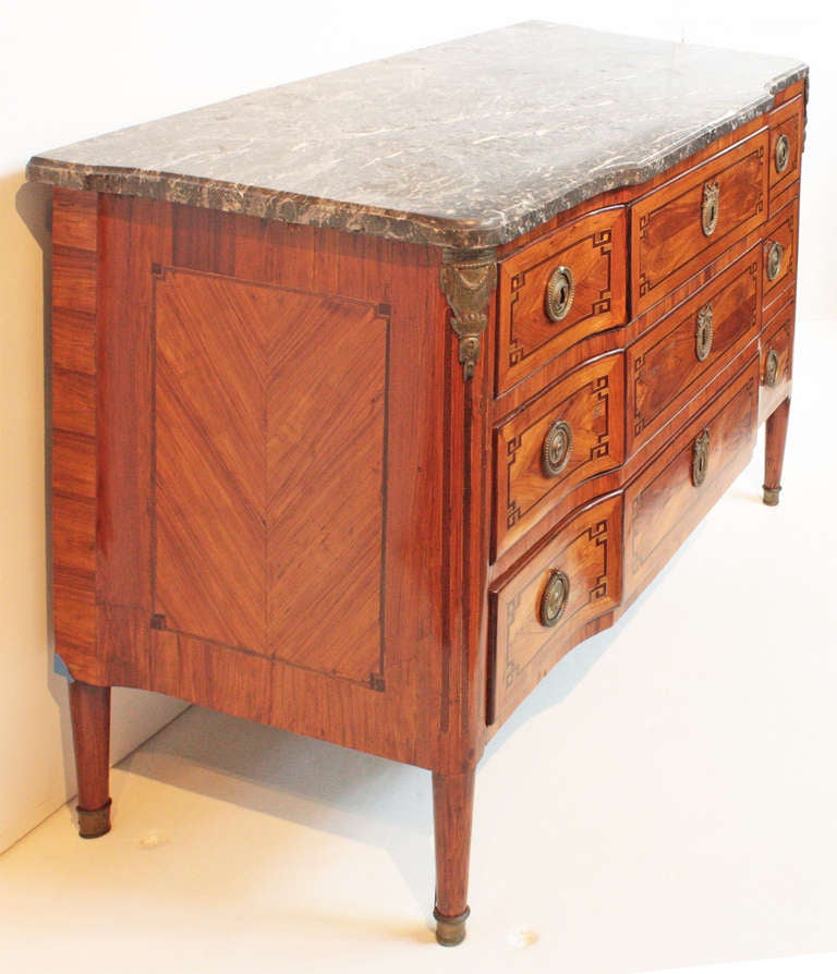 A fine Louis XVI five-drawer chest with gilt bronze trim at sides and feet, three top drawers (small drawer at each side of larger, slightly extruded center drawer), two large drawers below 

fancy veneer trim around edges, inside drawer fronts