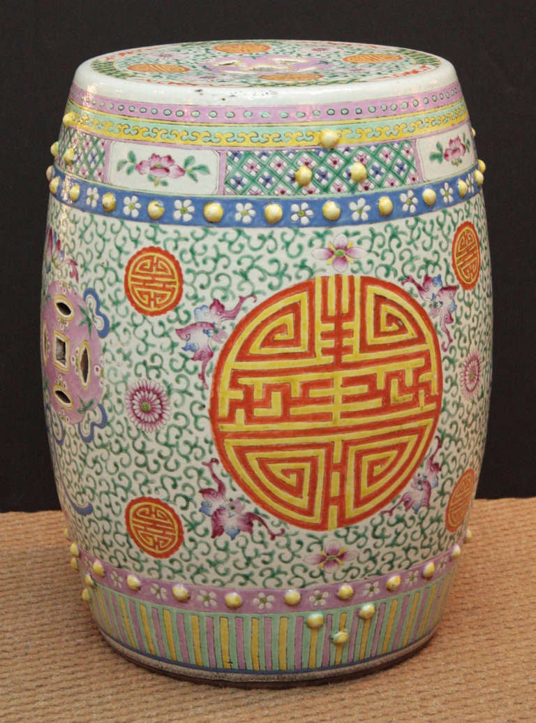 a a brightly colored Chinese garden stool of porcelain with reds and blues on white background, also yellow, violet, turquoise and green, overall pearl designs

great color and pattern

top surface has a 12