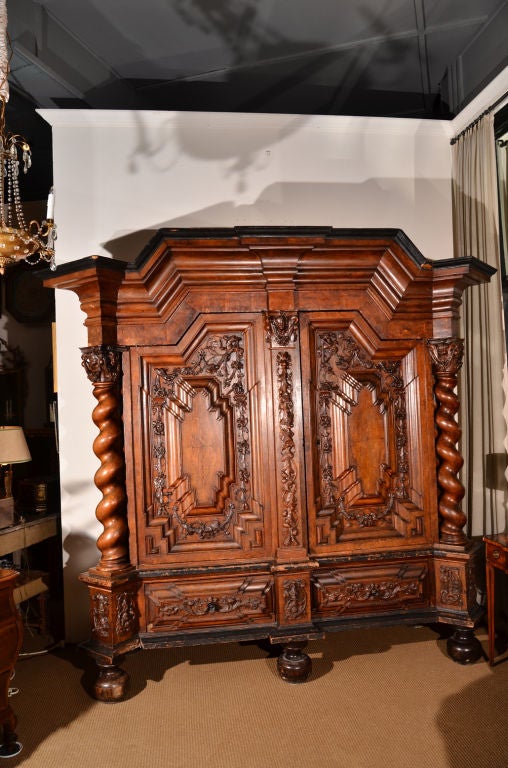 A large 17th century Dutch Kas / wardrobe / clothes press of carved walnut. Single bodied, two doors highly carved with floral swags. Twisted columns at the sides are topped by angel's faces. There is a single drawer, each side, at the bottom. The