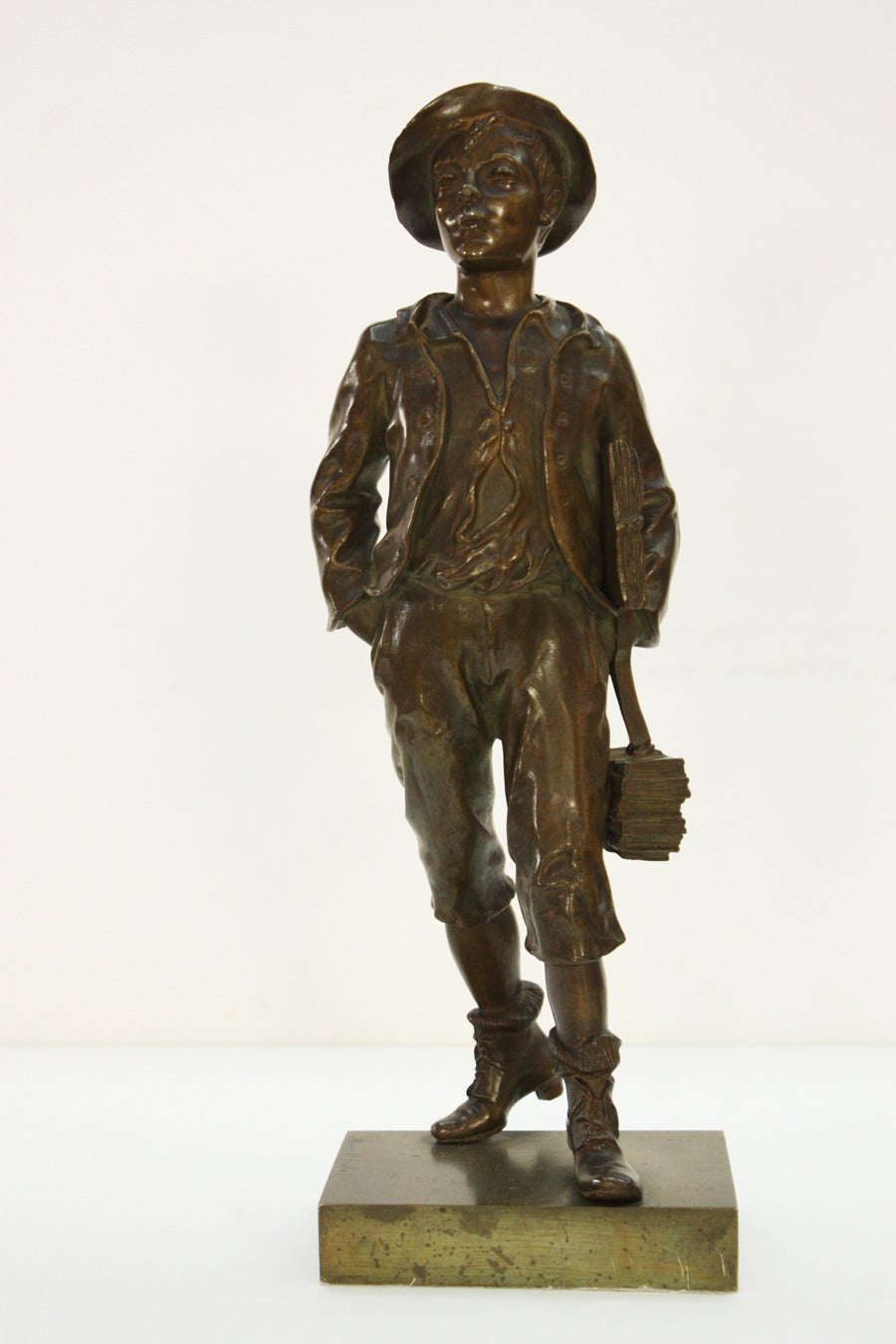 A bronze statue of a young schoolboy with his hand in his pocket and carrying books. Signed Marcel Debut  rouge on the  base (see image 6)