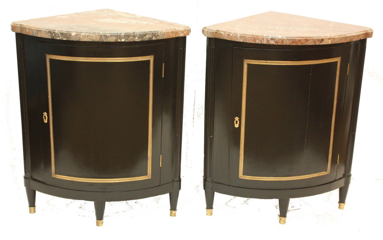 A pair of demi-lune directoire cabinets with curving door fronts and thick marble tops. Ebonized later with gilt trim on doors and feet.