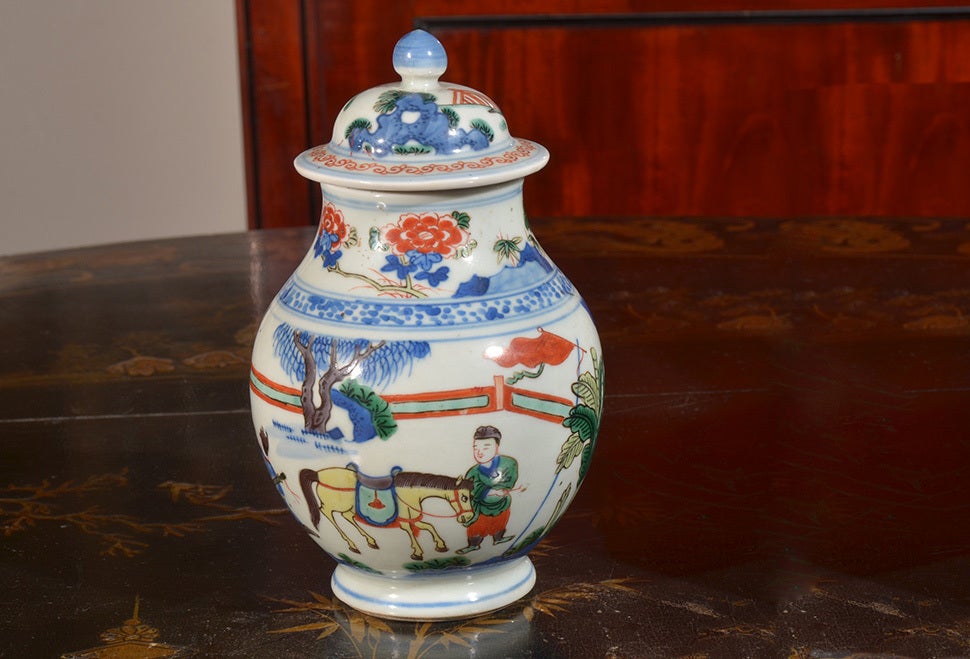 A Doucai jar with lid. People and horse in landscape are around the center. Blue, green, and red predominate on white