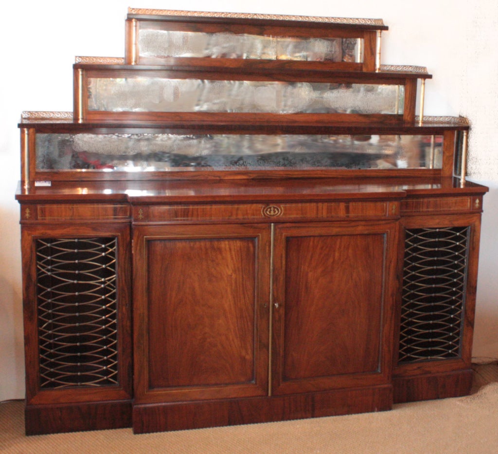 a large Regency side cabinet / chiffonnier 

below: a center pair of solid panel doors flanked by grill doors 

above: graduated, mirror backed shelves with pierced brass gallery, shelves supported by brass columns