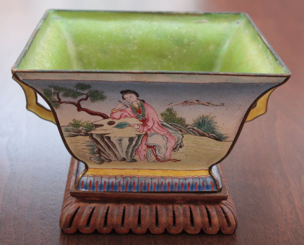 a pair of Chinese enamelled square dishes with chartreuse interiors - pale turquoise on the exteriors with scenery and people. Carved wooden stands.