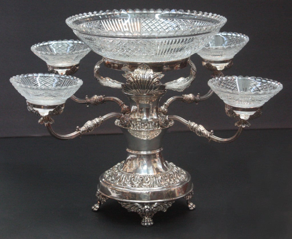a silver plated epergne with cut glass center bowl and four smaller bowls on arms, heavily repousse'd band on base, at top, and on bowl holders, as well as paw feet