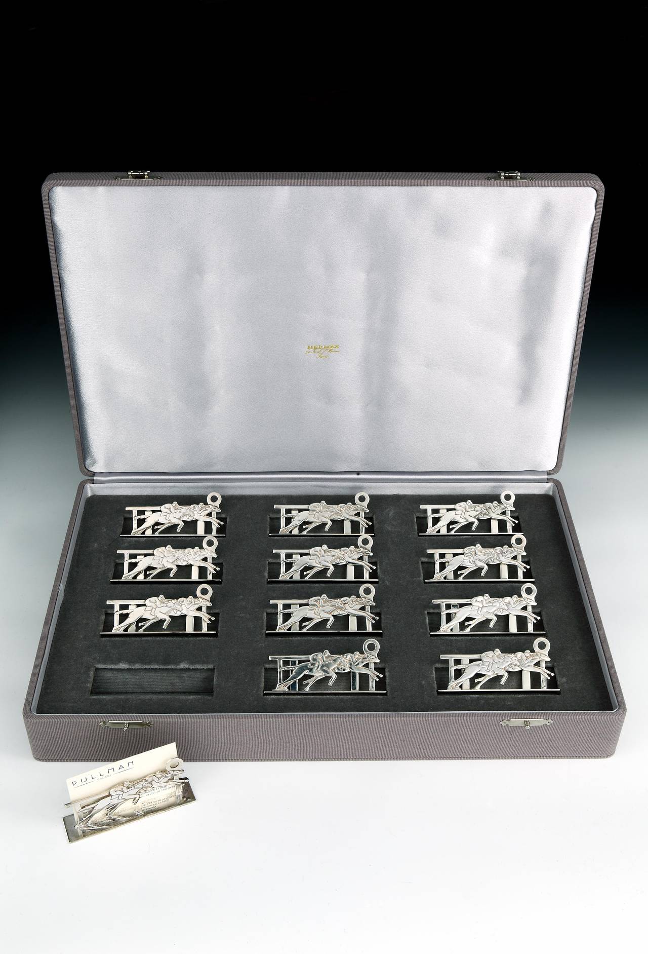 A fine set of 12 sterling silver Art Deco-style place-card or menu holders in the form of two racehorses crossing the winning post.

Each holder stamped Hermés Paris to the base. The set has a fully refurbished, grey grosgrain Hermés