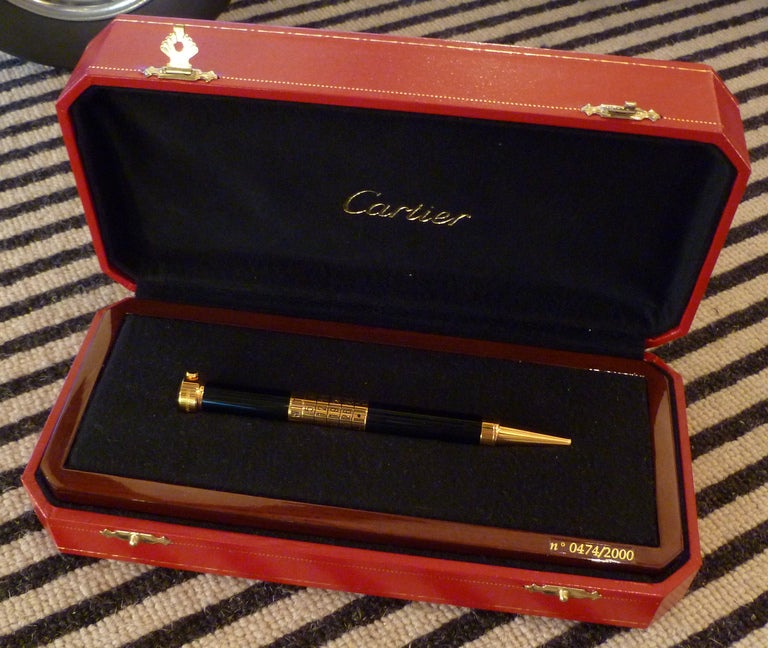 A very fine, limited-edition Gentlemans compendium ballpoint pen, one of only 2000 made featuring a 6-barrel calendar set within the shaft of the black lacquered pen, with gilded metalwork marked CARTIER, with an inbuilt miniature clock to the end