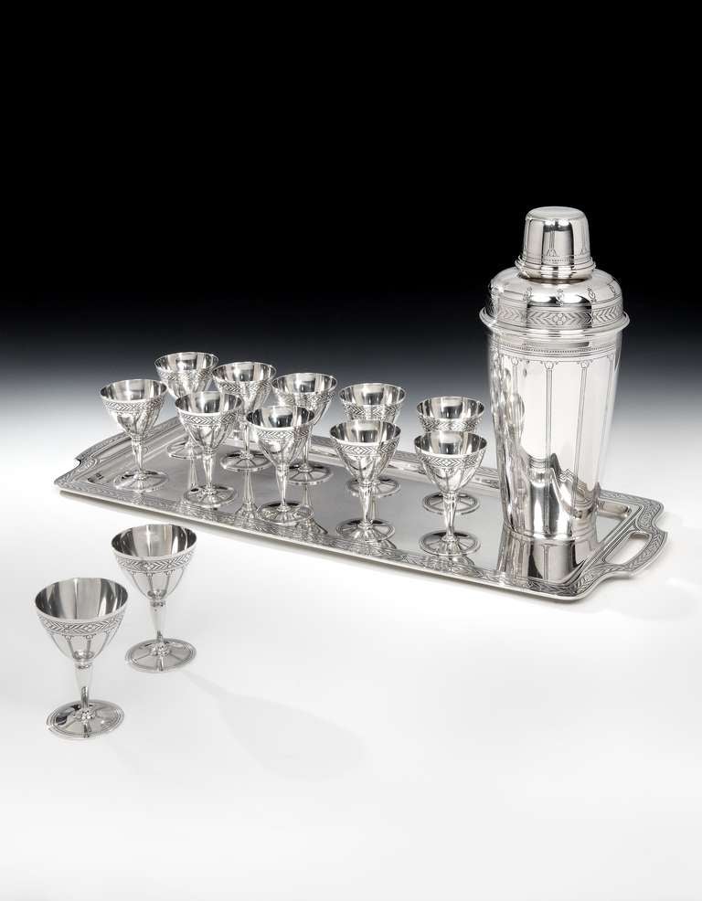 A spectacular Art Deco sterling silver 14-piece cocktail set, comprising of a massive 4½ pint cocktail Shaker, (the largest Tiffany produced), with a highly decorative, foliate pierced strainer and heavy cap, with a suite of 12 cocktail goblets all