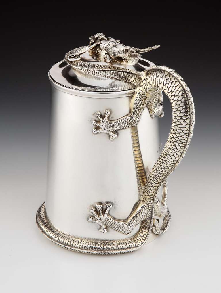 A beautiful and imposing Sterling silver flagon with gilded interior by Robert Hennell, with ornate detailing of a Chinese dragon acting as the handle, its tail wrapping around the sides and bottom edge, and its head resting on the hinged lid.