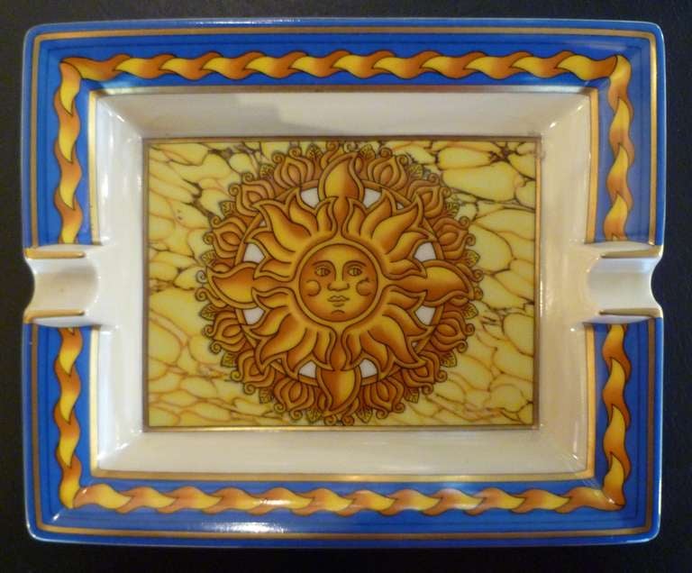 A pair of oblong porcelain cigar ashtrays of typical style, each with decoration of the sun against a marble ground, within a blue-ground border. Each marked HERMES PARIS to one side and MADE IN PARIS to the opposite, the bases, suede covered.