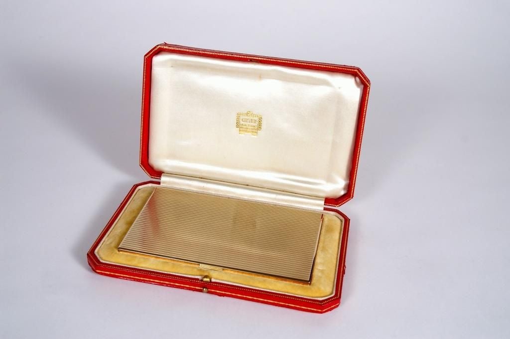 An exceptionally rare and beautifully-made 9 carat solid gold Art Deco-style cigarette case; manufactured by Cartier in London, c. 1940. Bearing Cartier London engraved marks as well as English 9 carat gold hallmarks, the case has its original red