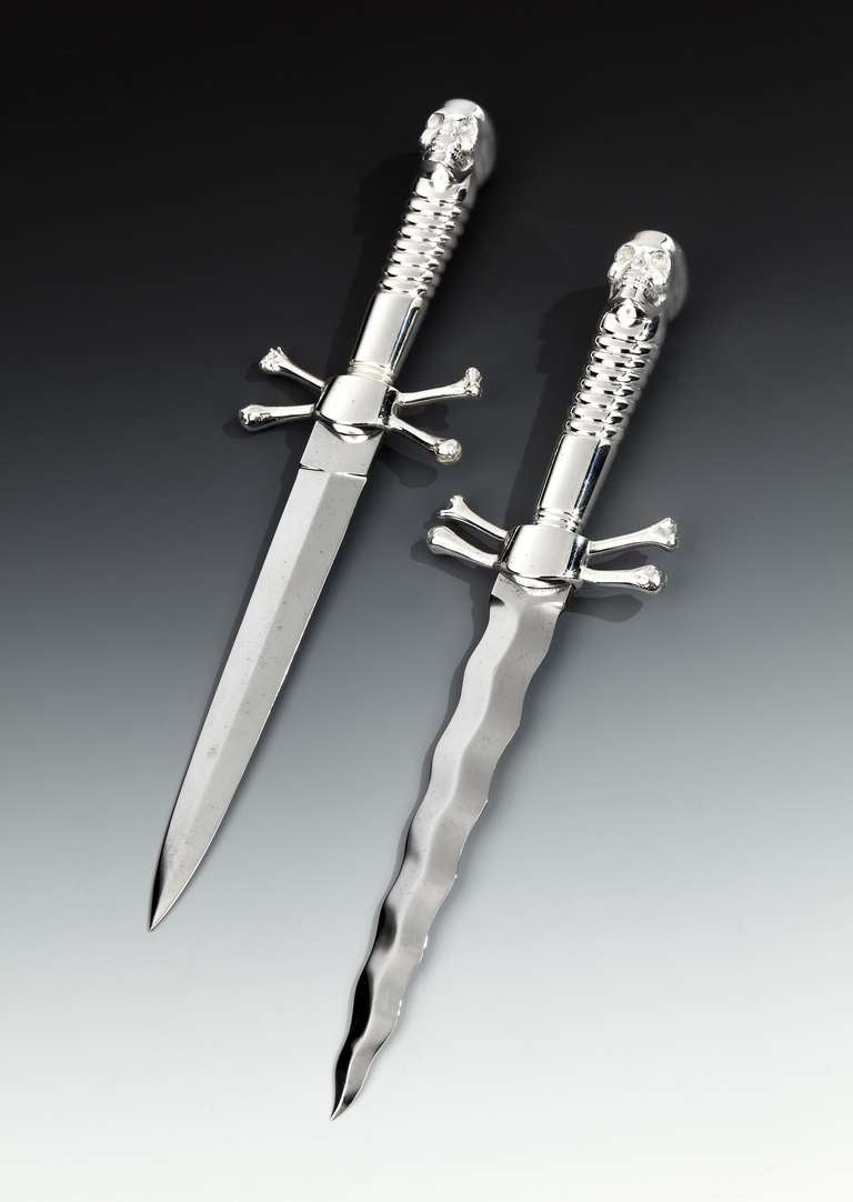 Two imposing late 19th Century daggers, possibly with Masonic or ceremonial connotations, with heavy cast silvered bronze skull and crossbones handles and steel blades (one straight, one wavy). 

English. Circa 1890.