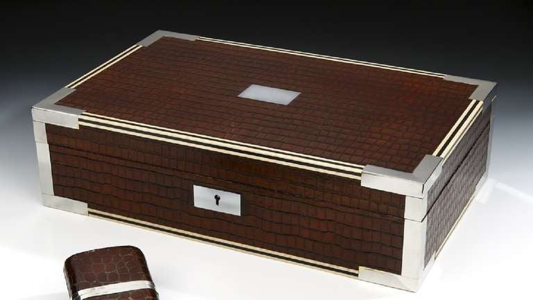 A modern, fully functional cigar humidor, the interior with modern humidified storage for cigars with four compartments and movable dividers, the exterior in faux-crocodile, with blond and dark wood stringing to the edges, and silvered corner